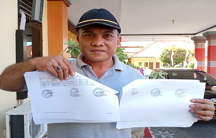 Ketua Komite SDN 4 Selat, Putu Ardika menunjukkan perbedaan TTD pada berkas sekolah. Ia mengadukan kepala dan bendahara SDN 4 Selat yang diduga memalsukan TTD-nya.