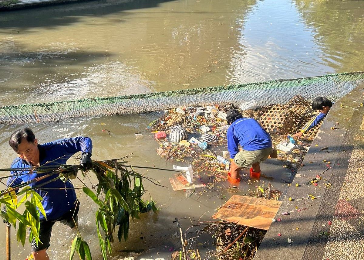 BERSIHKAN SAMPAH: Petugas kebersihan dan PUPR Kota Denpasar mengangkat dan mengangkut sampah yang dibungkus plastik hanyut di Tukad Badung (20/6/2024).