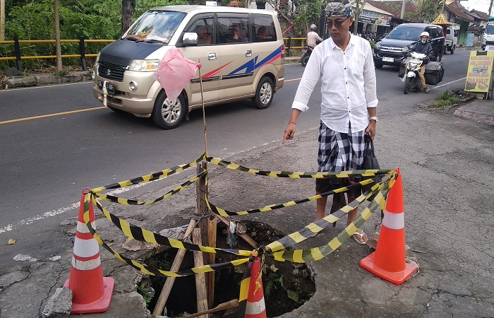 Kaling Samplangan Wayan Gede Redana menunjukkan lubang di sudut Jalan Sampangan-Jalan Puseh yang berlubang dan membahayakan.