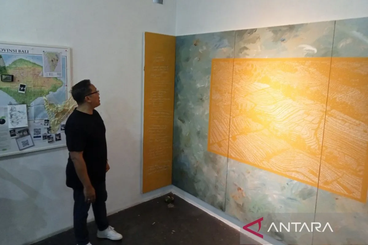 Seniman Putu Winata saat melihat karya seri lukisannya yang bercerita tentang Subak, sebuah sistem irigasi pertanian khas Bali. Pameran itu digelar di Kedai Kebun Forum Yogyakarta.