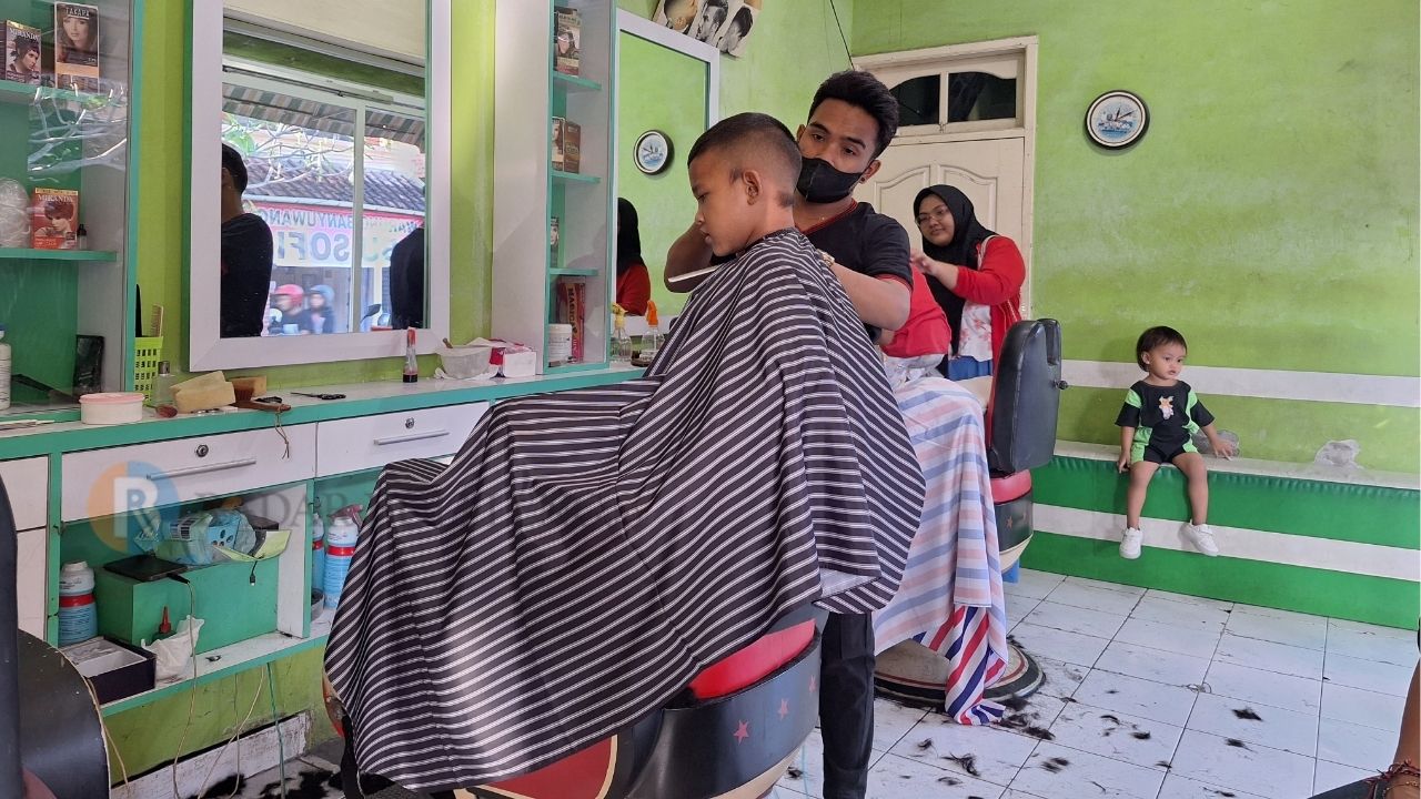 RAMAI PENGUNJUNG: Anak-anak berbondong-bondong cukur rambut di salah satu barbershop kawasan Denpasar, kemarin (14/7/2024).