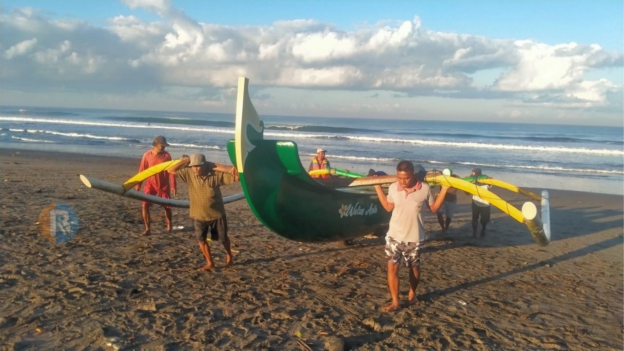 PULANG MELAUT: Nelayan di Pantai Yeh Gangga Tabanan tampak menggeser perahu mereka, setelah melaut.