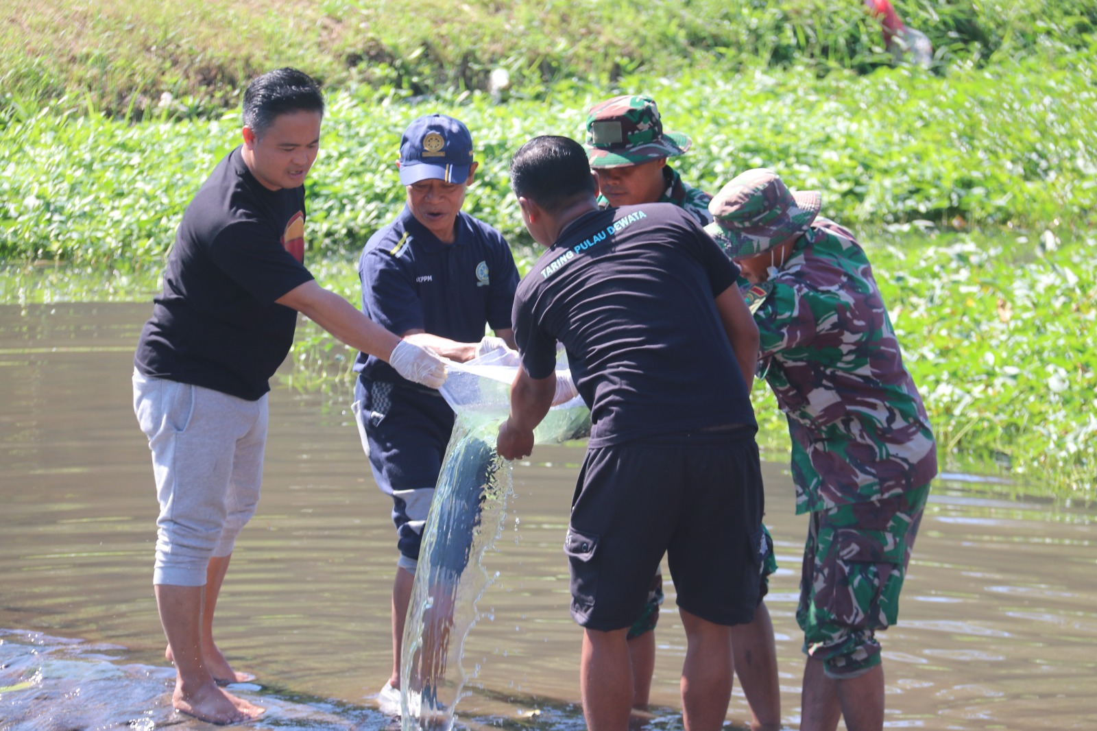 TEBAR IKAN: Perbekel Lokapaksa, Putu Dodi Triana (paling kiri) melakukan aksi penebaran benih ikan di Tukad Unda.