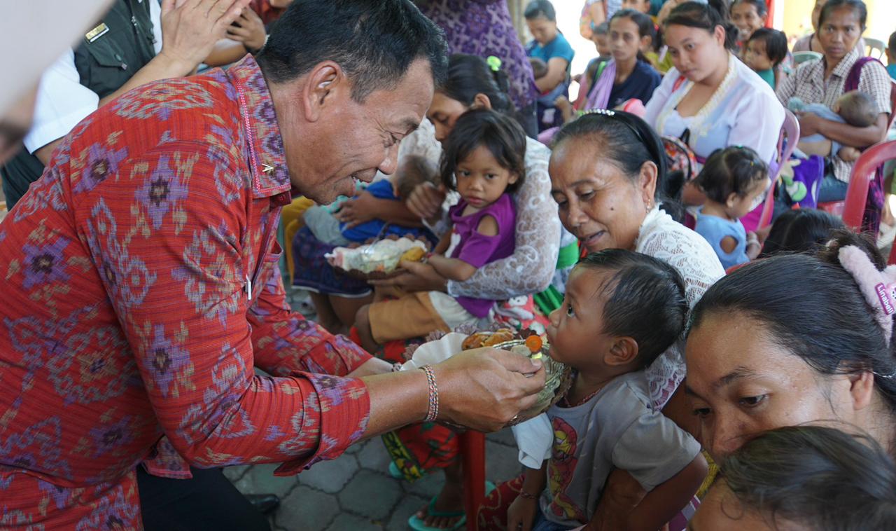 PANGAN SEHAT: Pj. Bupati Buleleng Ketut Lihadnyana (kiri) saat memberikan pangan sehat kepada balita di Desa Lokapaksa.