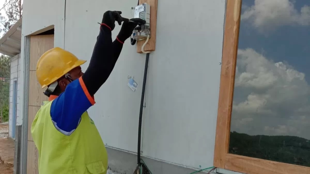 LISTRIK: Petugas tengah memasang instalasi listrik di salah satu rumah.