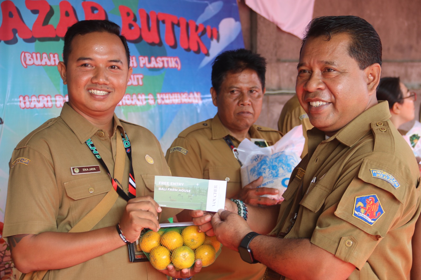 SAMPAH JADI BUAH: Plt. Kepala Dinas Lingkungan Hidup Buleleng, Gede Melandrat (kanan) menyerahkan buah dan voucher kepada staf dinas.