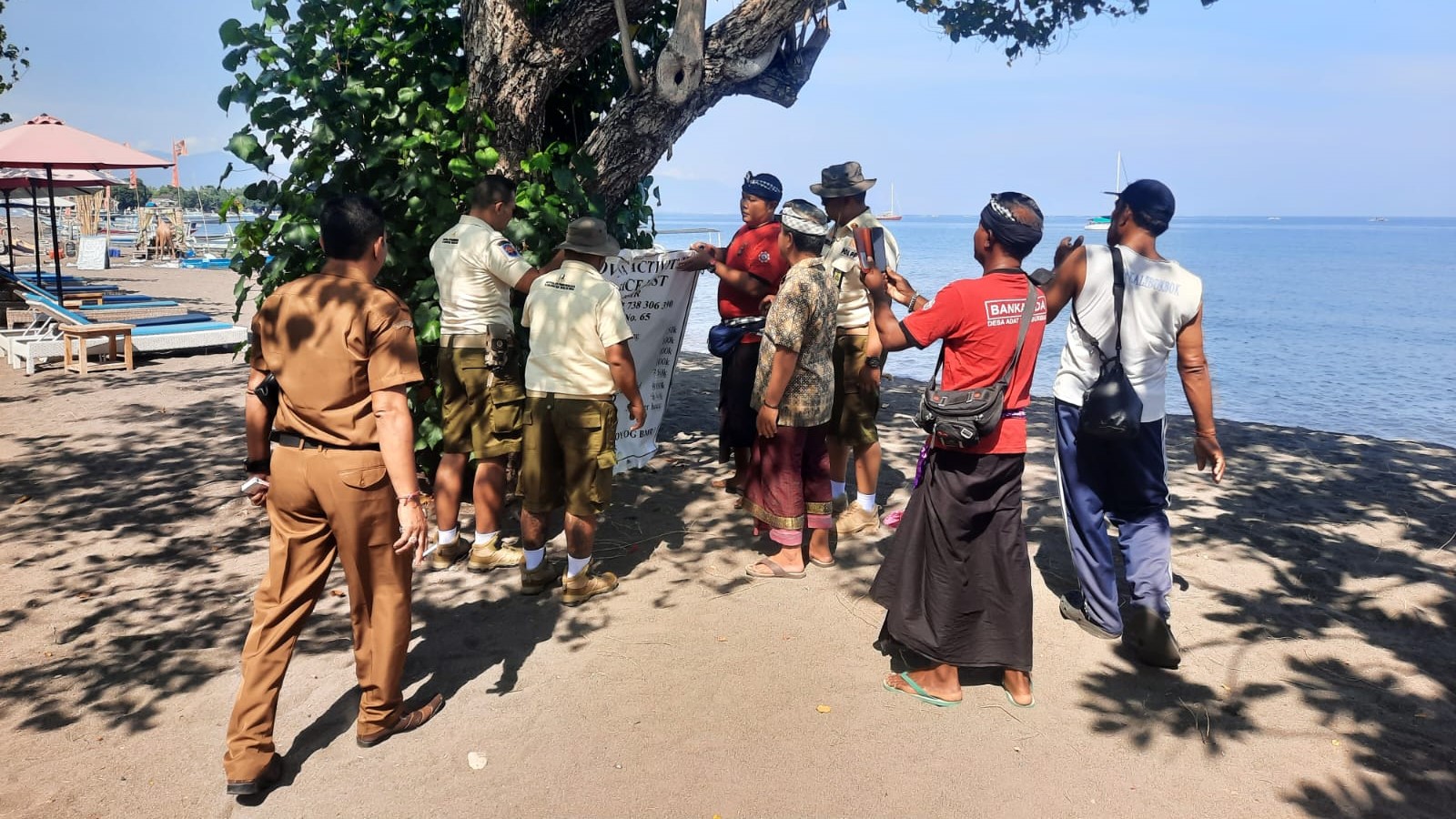 TERTIBKAN BANNER: Pol PP Pariwisata bersama aparat desa dinas dan desa adat menertibkan banner liar yang dipasang di area Pantai Kalibukbuk.