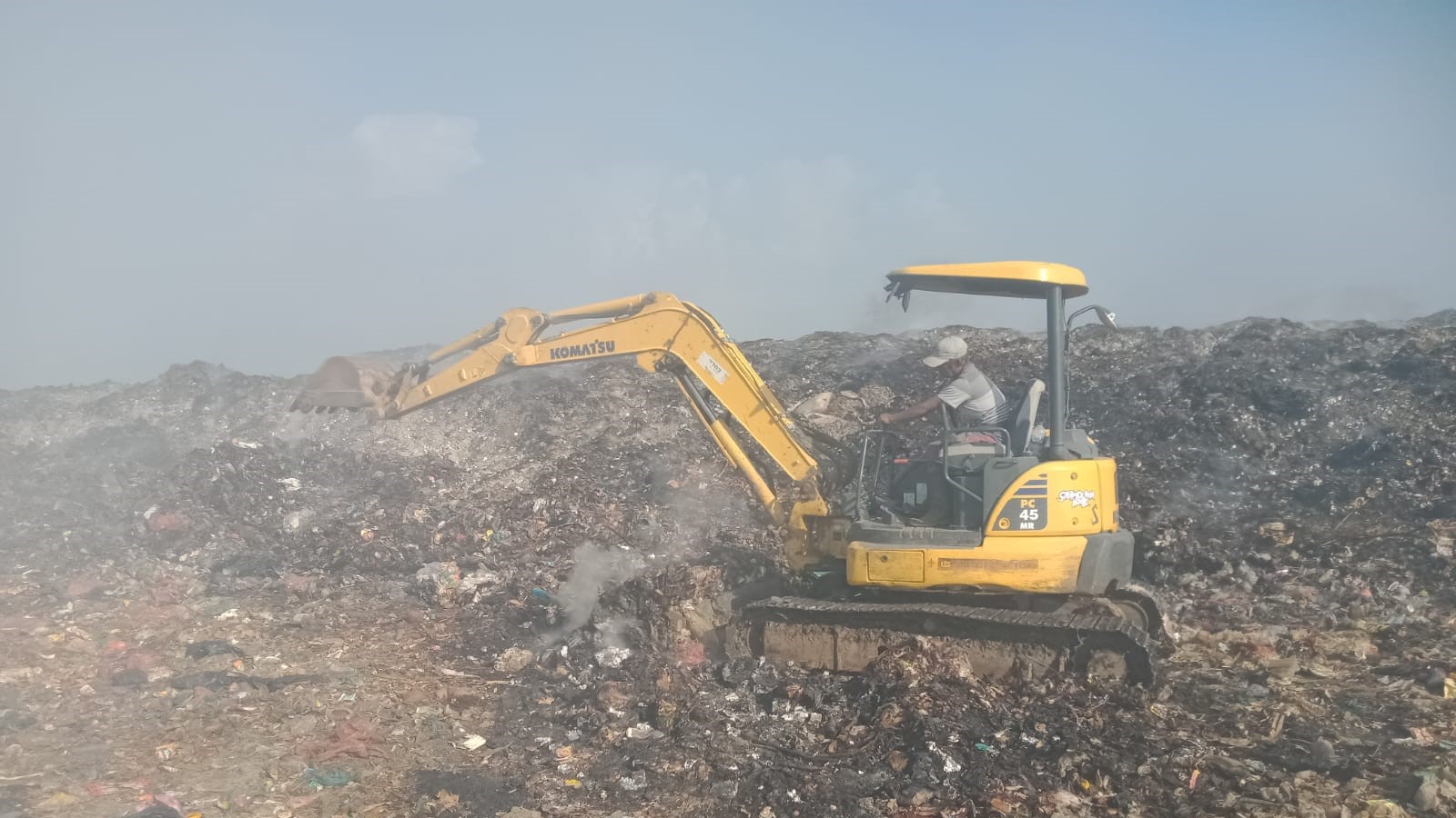 BONGKAR SAMPAH: Ekskavator dikerahkan untuk membongkar timbunan sampah di TPA Bengkala yang masih mengepulkan asap.