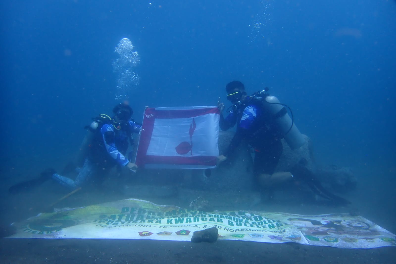MENYELAM: Pramuka Saka Bahari melakukan penyelaman di perairan Desa Pacung. Dalam penyelaman itu, bendera Pramuka juga dikibarkan.
