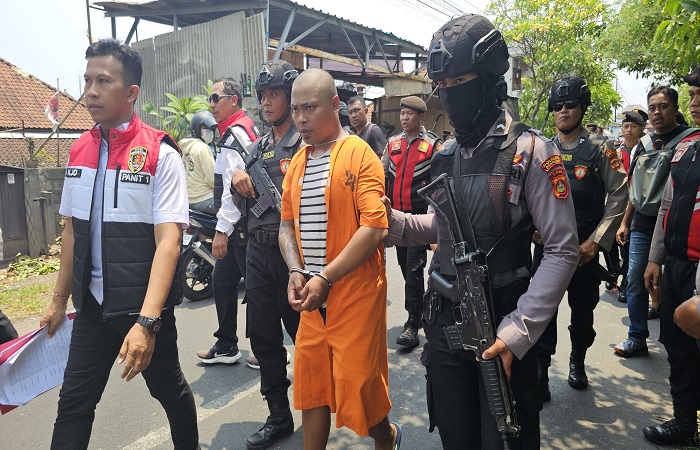 Tersangka Agus Sugianto, 31, dikawal polisi saat rekonstruksi di bantaran sungai Taman Pancing Timur, Denpasar Selatan, Selasa (12/11/24). Dia dengan sading menghabisi nyawa temannya sendiri.