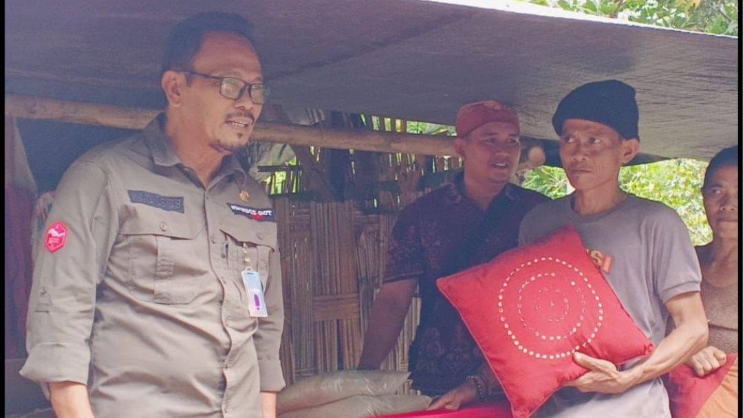 BERI BANTUAN: Kepala Dinas Sosial Buleleng, Putu Kariaman Putra (kanan) menyerahkan bantuan kepada Kadek Darmika, warga miskin di Desa Tukadsumaga yang rumahnya ambruk terhempas angin kencang.