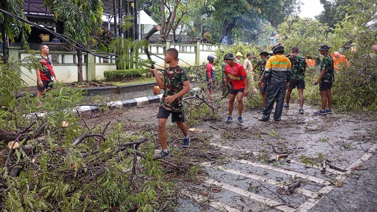 BERSIHKAN JALAN: Personel TNI dari Batalyon Raider dan BPBD Buleleng kerja bakti membersihkan ranting dan dahan pohon.
