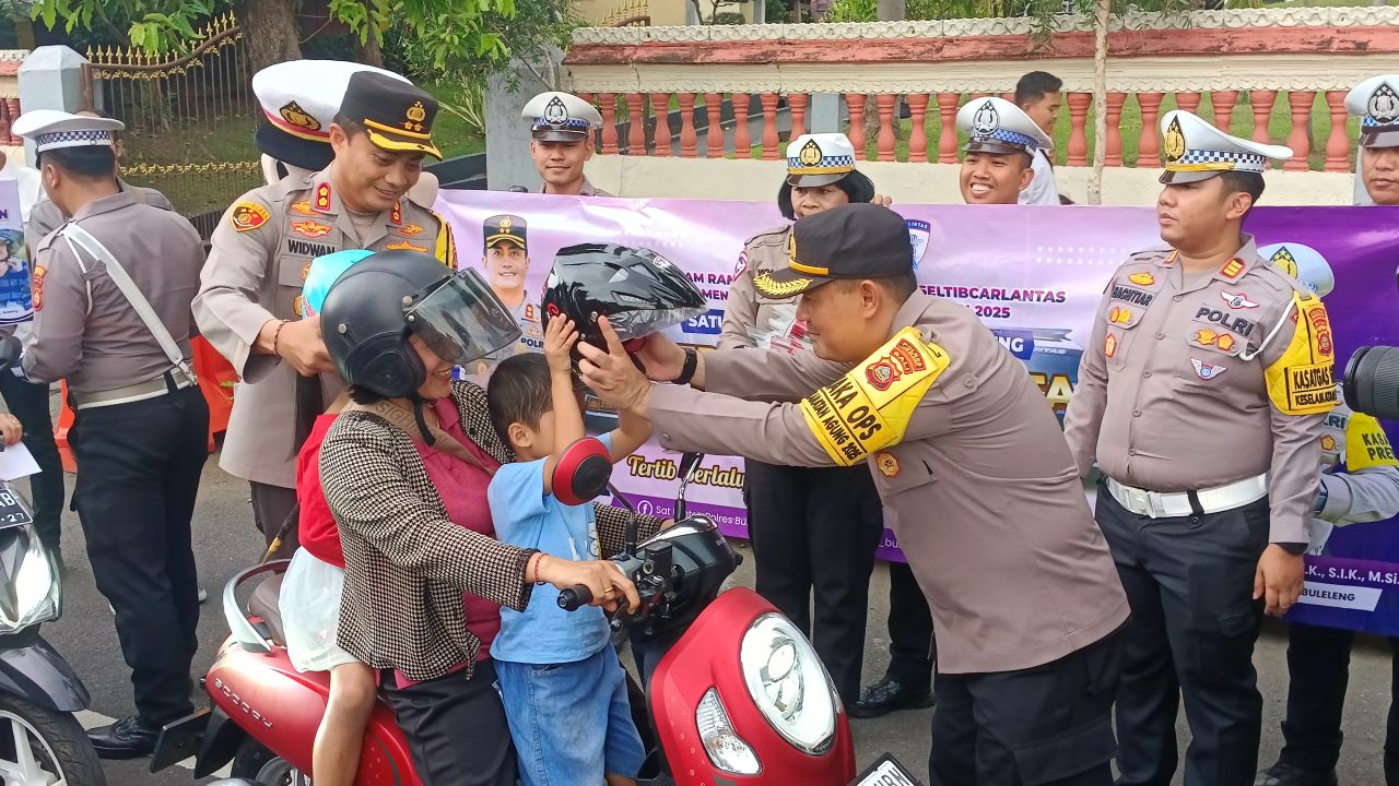 PAKAI HELM YA DIK!: Kapolres Buleleng AKBP Ida Bagus Widwan Sutadi (kiri) dan Wakapolres Buleleng Kompol Fudin Ismail (kanan) memasangkan helm pada anak-anak pengguna jalan.