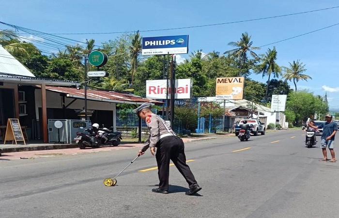 Polisi melakukan olah TKP di lokasi kecelakaan antara dua sepeda motor. Satu orang tewas akibat peristiwa tersebut.