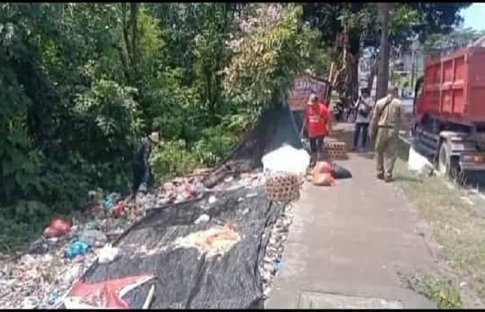 Petugas kebersihan dari DLH Tabanan membersihkan sampah dan memasang paranet serta tanda larangan di salah satu TPS liar di pinggir Jalan By Pass Ir Soekarno, Tabanan.