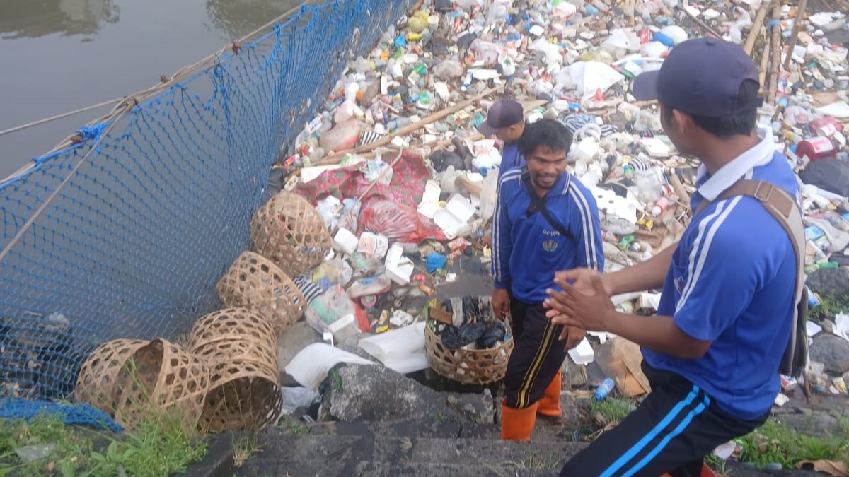 BERSIHKAN SAMPAH: Petugas Dinas PUPR Denpasar membersihkan sampah yang dibuang ke sungai. Puluhan ton sampah dibuang ke sungai setiap harinya.