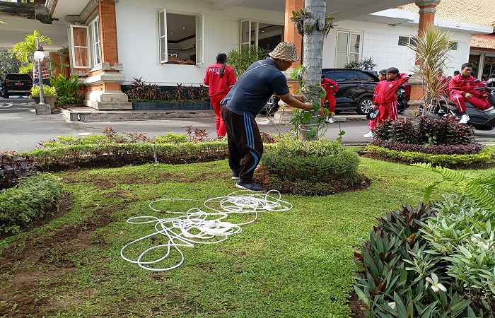 Salah satu staf Dinas Kominfosanti Buleleng memasang lampu di halaman depan kantornya. Ini merupakan salah satu realisasi SE lampu hias dari bupati Buleleng.