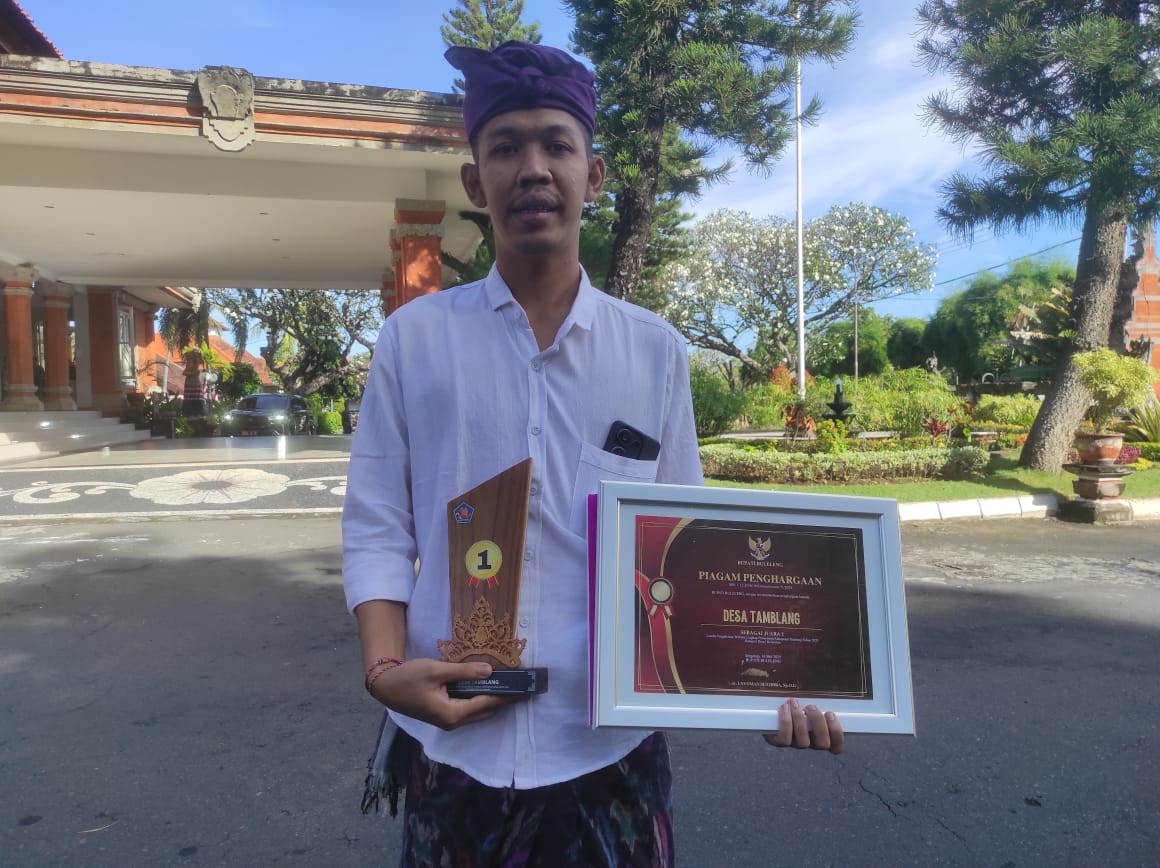 RAIH PRESTASI: Operator website di Desa Tamblang, Komang Adisusastra, menunjukkan trophy dan piagam penghargaan.