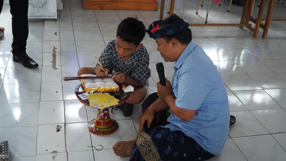 MASUK SEKOLAH: Salah seorang staf Museum Lontar Gedong Kirtya mengenalkan cara menulis pada daun lontar kepada siswa SD di Buleleng. Pengenalan itu merupakan bagian dari program Museum Masuk Sekolah.