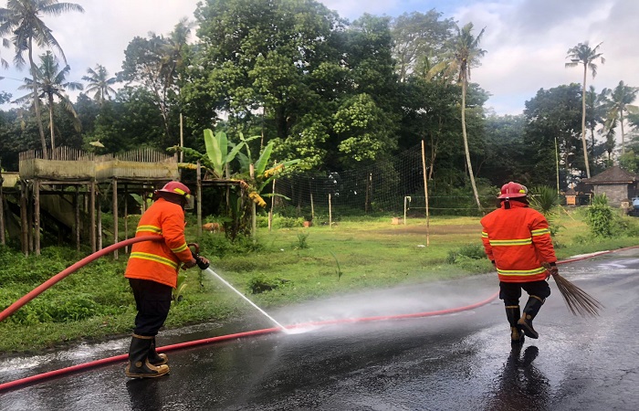 Petugas Damkartan Karangasem saat melakukan penyemprotan ceceran solar di wilayah Desa Ababi, Kecamatan Abang, Karangasem, Minggu (8/6) kemarin.