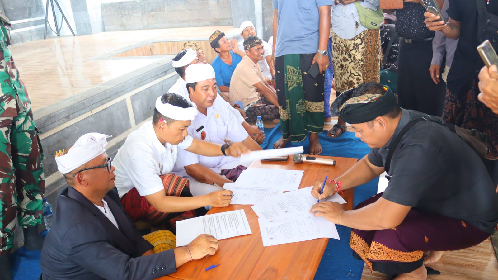 SEPAKAT BERITA ACARA: Kelian Desa Adat Pejarakan, Putu Suastika (baju hitam kiri) menandatangani berita acara kesepakatan sebagai tindak lanjut aspirasi krama.