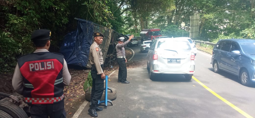 TERGULING: Sebuah truk terguling di Jalan Raya Singaraja-Denpasar. Banyak truk mengalami kecelakaan karena pengemudi masih awam dengan jalur tersebut.