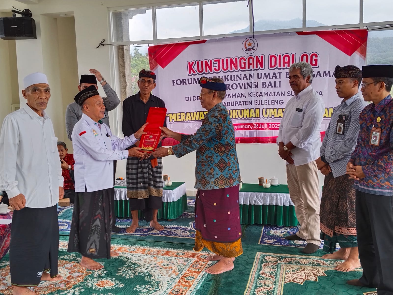 BICARA KERUKUNAN: Ketua Harian FKUB Bali, I Gusti Made Ngurah (baju endek) menyerahkan cindera mata kepada Imam Masjid Safinatussalam Desa Pegayaman.