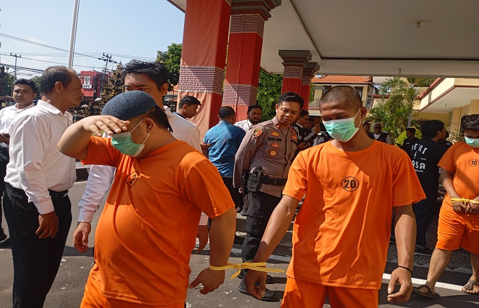 Tersangka AK (depan, bersongkok) dan DS (belakang) tampak malu ketika difoto awak media. Keduanya disergap polisi, ketika hendak melakukan transaksi sabu.