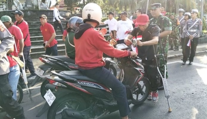 BAGIKAN BENDERA: Aksi komunitas disabilitas di Kabupaten Jembrana, Bali, yang membagikan bendera kepada warga.