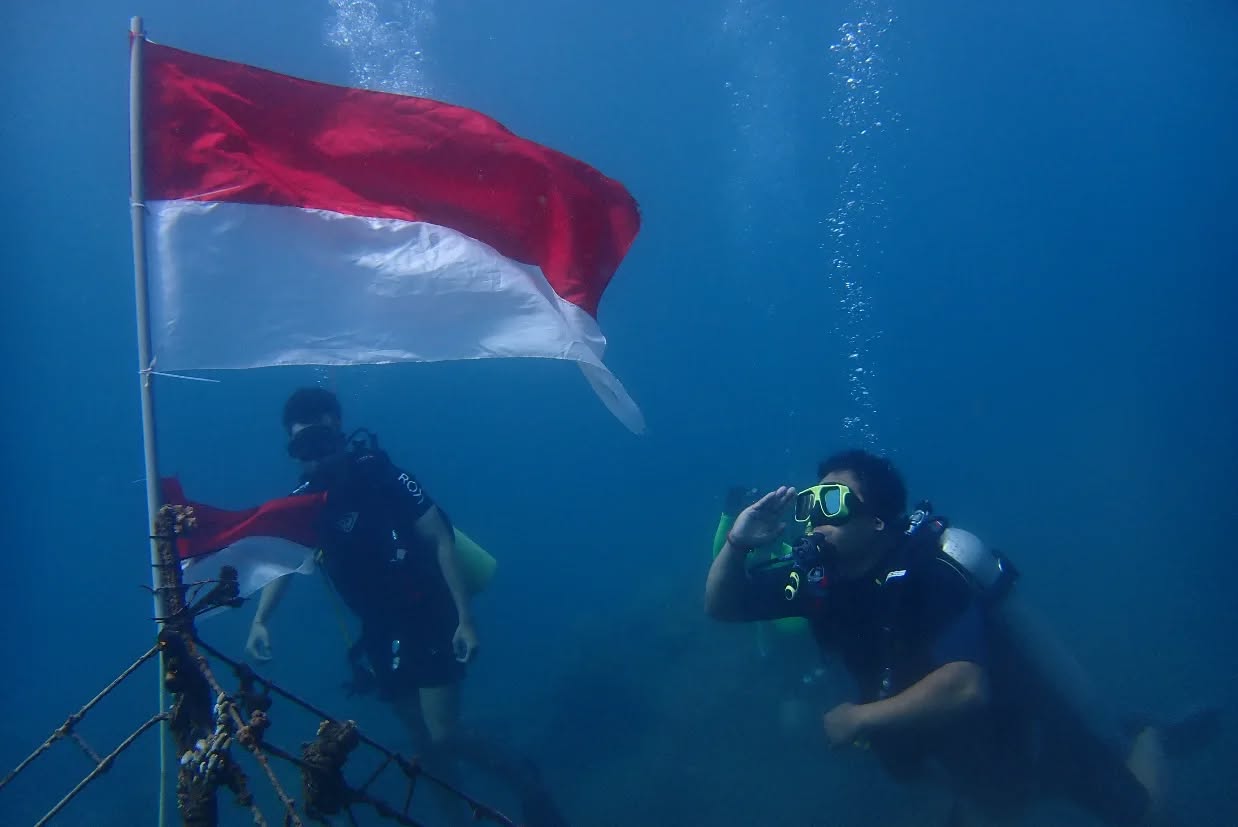 MENYELAM: Para penyelam di Buleleng melakukan upacara bendera di bawah air.