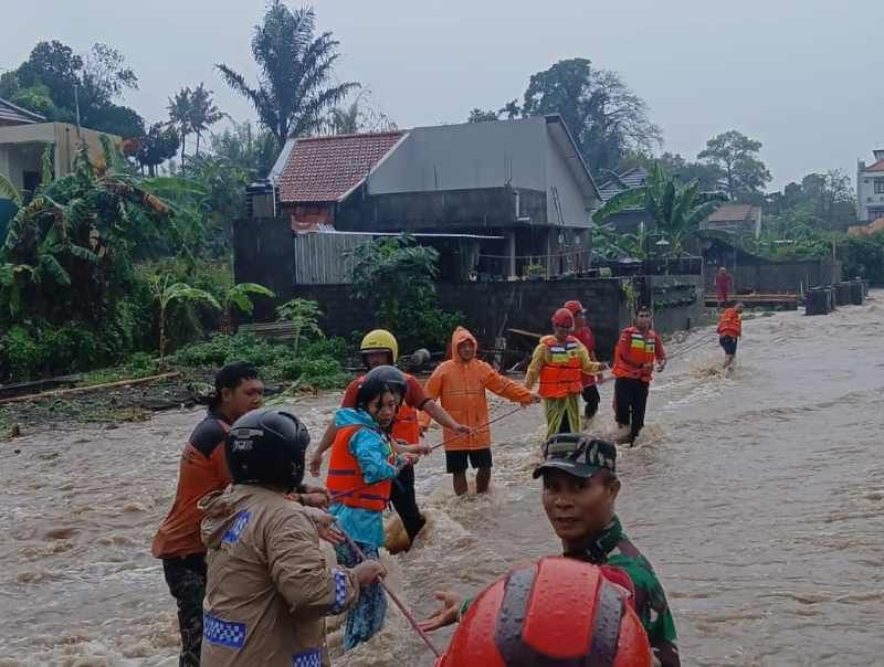 EVAKUASI: Petugas dari BPBD Gianyar berusaha mengevakuasi warga yang terjebak banjir.