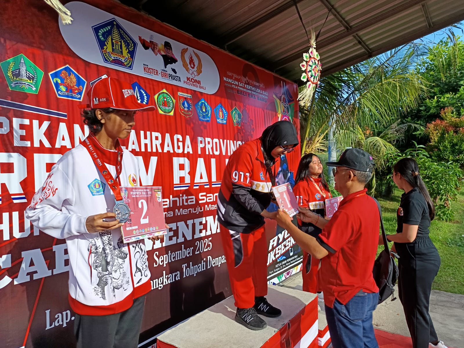 KALUNGKAN MEDALI: Ketua Umum KONI Buleleng, Ketut Wiratmaja (baju merah) mengalungkan medali kepada atlet menembak Buleleng yang berhasil  meraih medali emas.