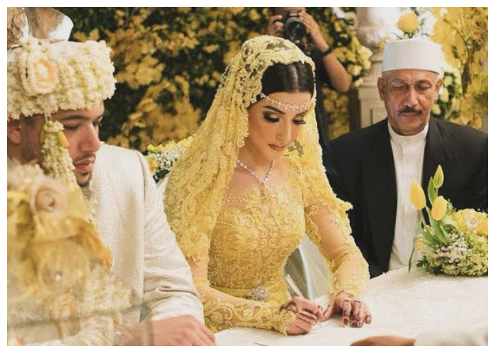 Momen ini diabadikan saat akad nikah. Tasya Farasya tampil anggun dalam balutan gaun pengantin warna kuning lengkap dengan kerudung renda berhias detail mewah.