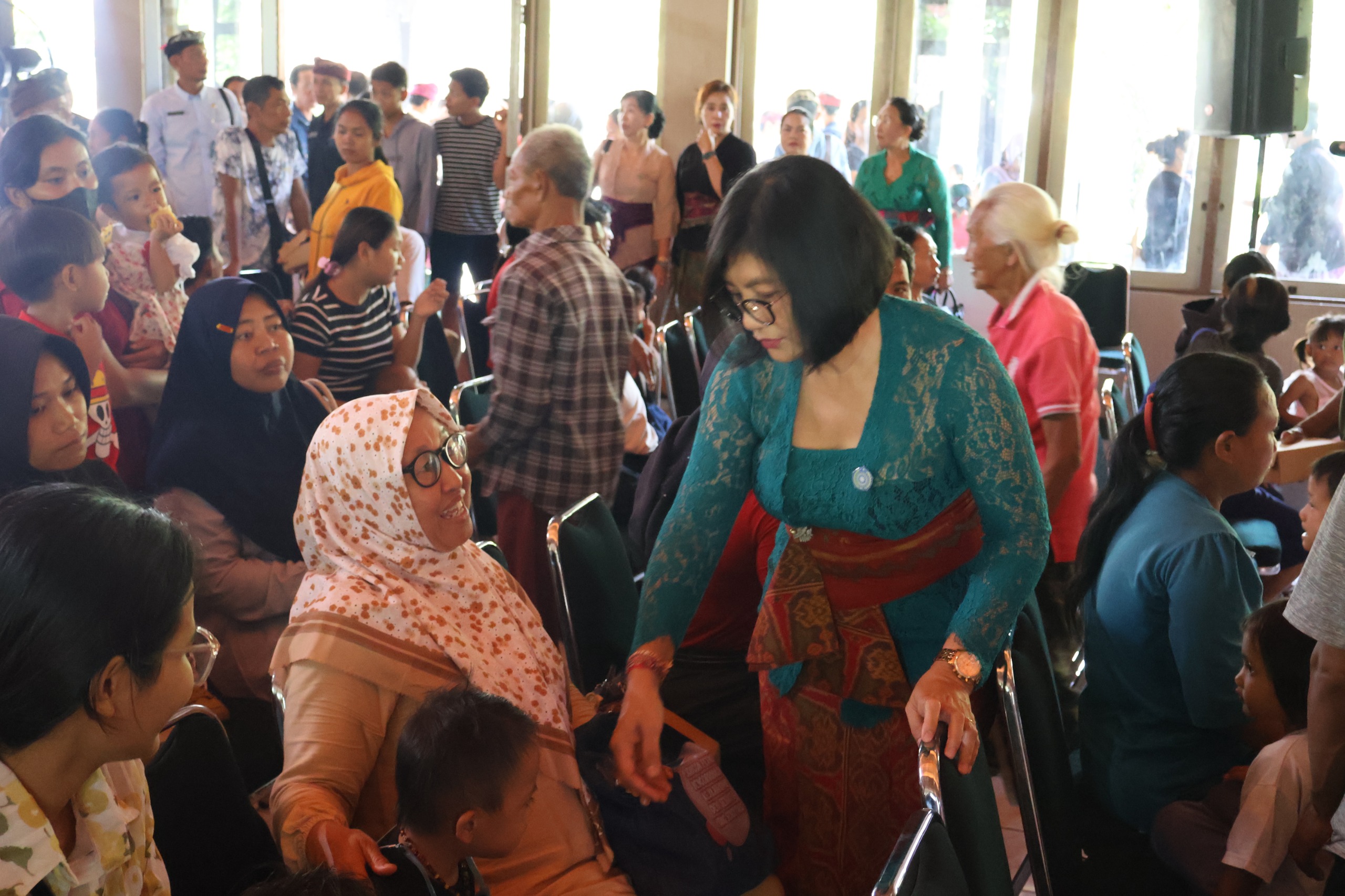 BAGIKAN PANGAN: Sekretaris Tim Penggarak PKK Buleleng (kebaya hijau) tampak bercengkrama dengan warga calon penerima bantuan pangan.