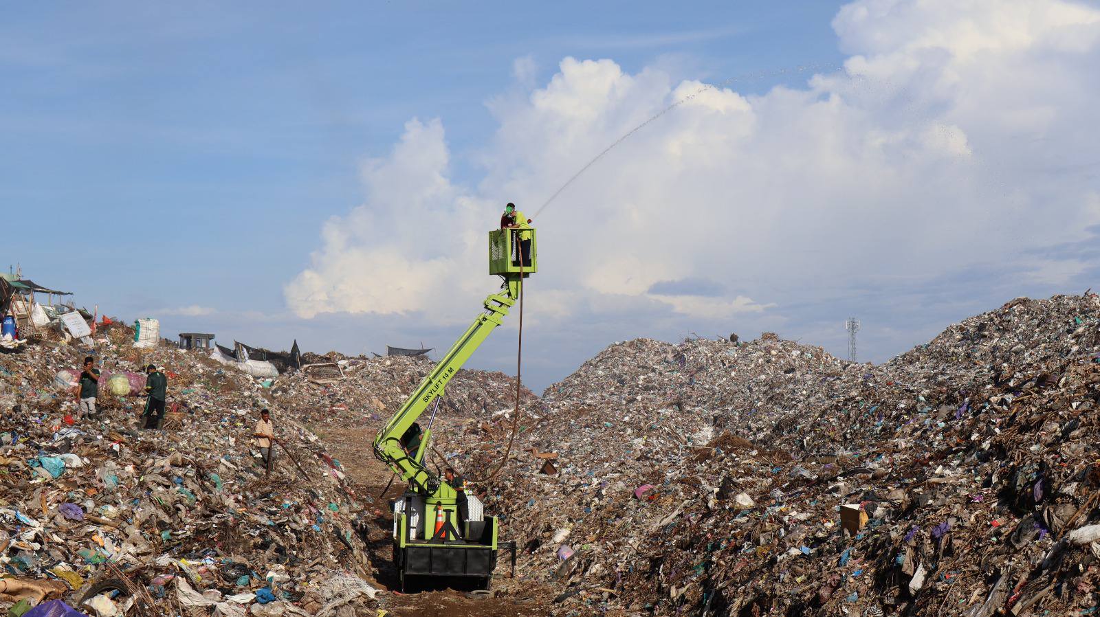 SEMPROTKAN CAIRAN: Proses penyemprotan eco enzyme ke tumpukan sampah yang menggunung di TPA Bengkala.