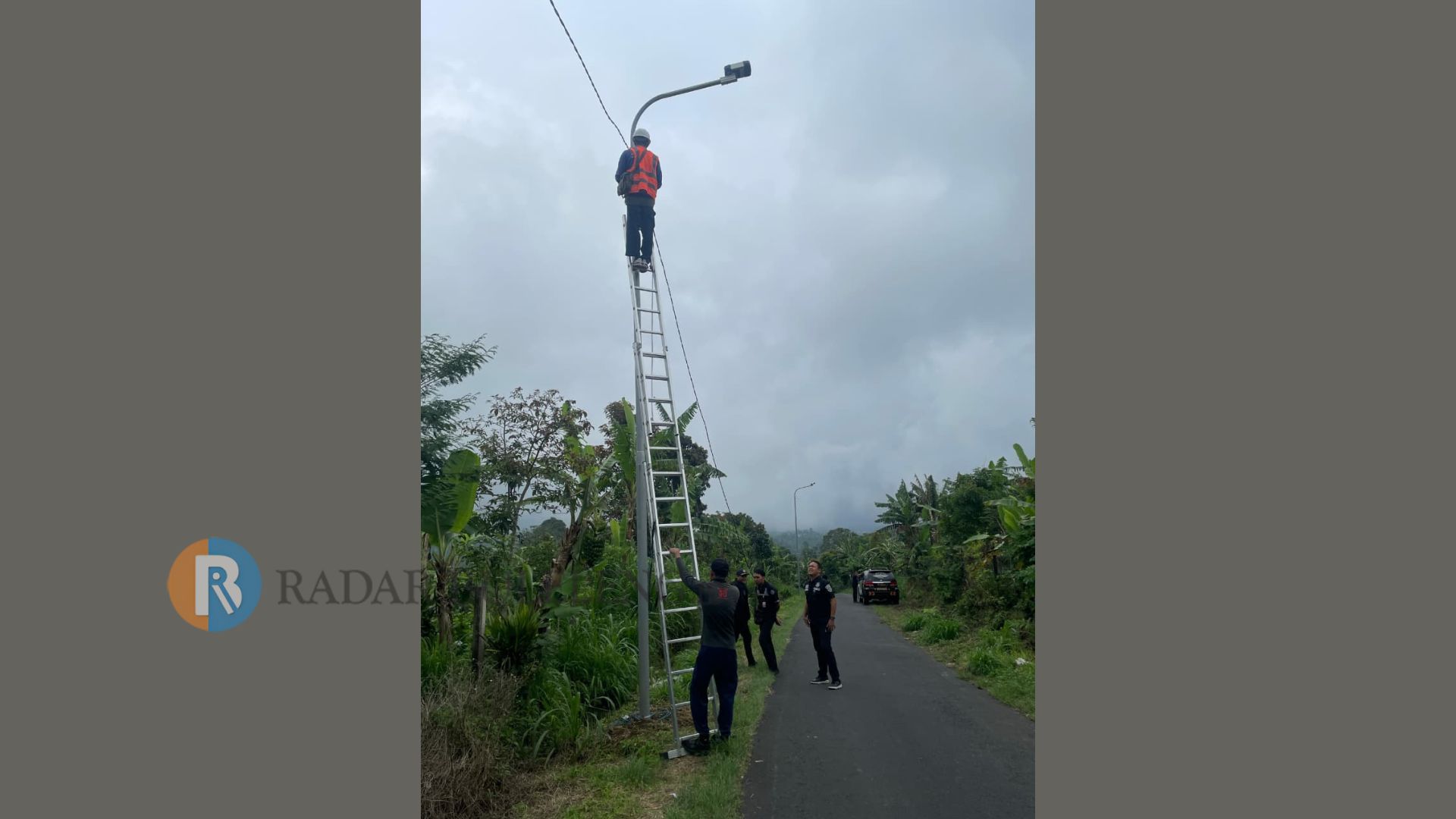PASANG LAMPU: Petugas Dinas Perhubungan Buleleng dan PLN memasang tiang dan lampu penerangan jalan di kawasan Desa Wanagiri.