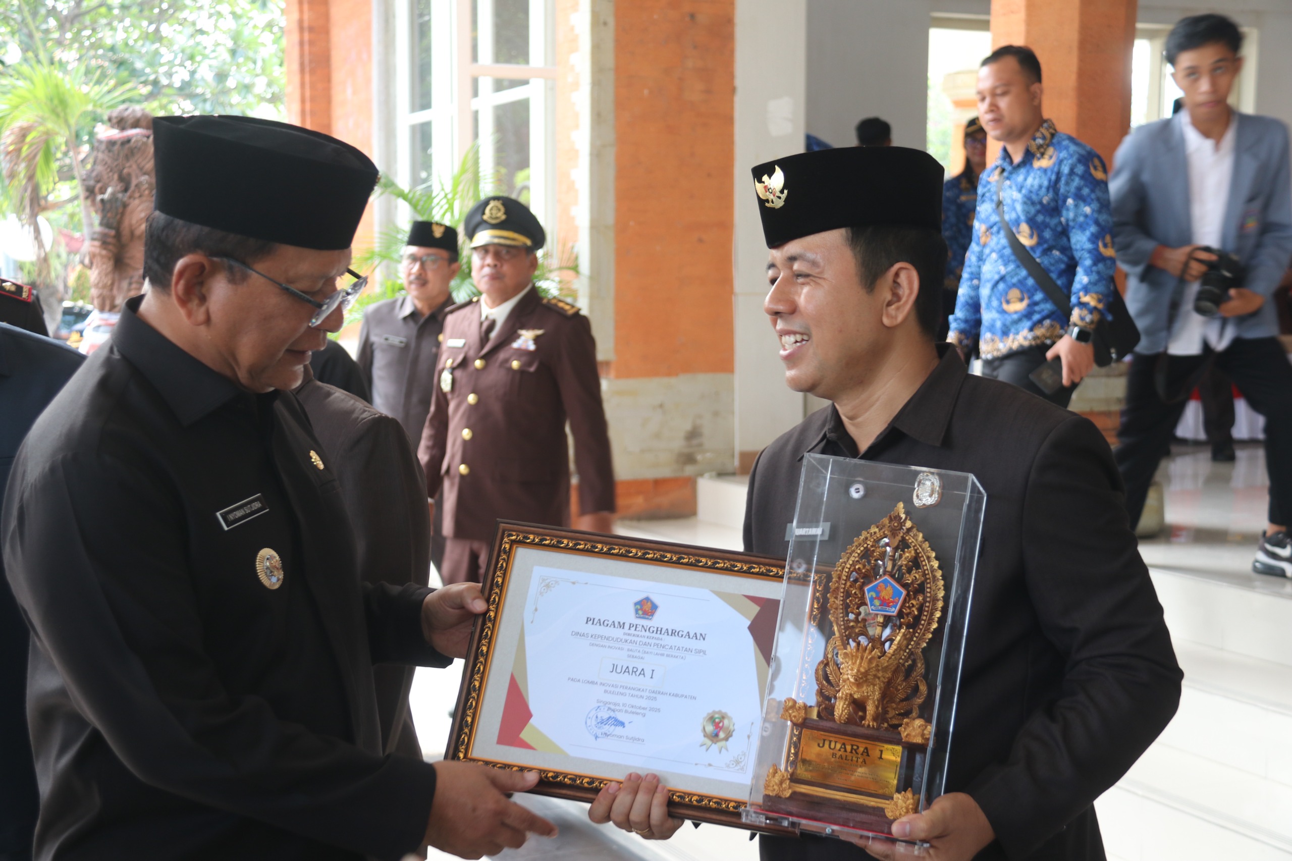 TERIMA PENGHARGAAN: Bupati Buleleng, I Nyoman Sutjidra (kiri) menyerahkan penghargaan kepada Kepala Dinas Dukcapil Buleleng, Made Juartawan (kanan).