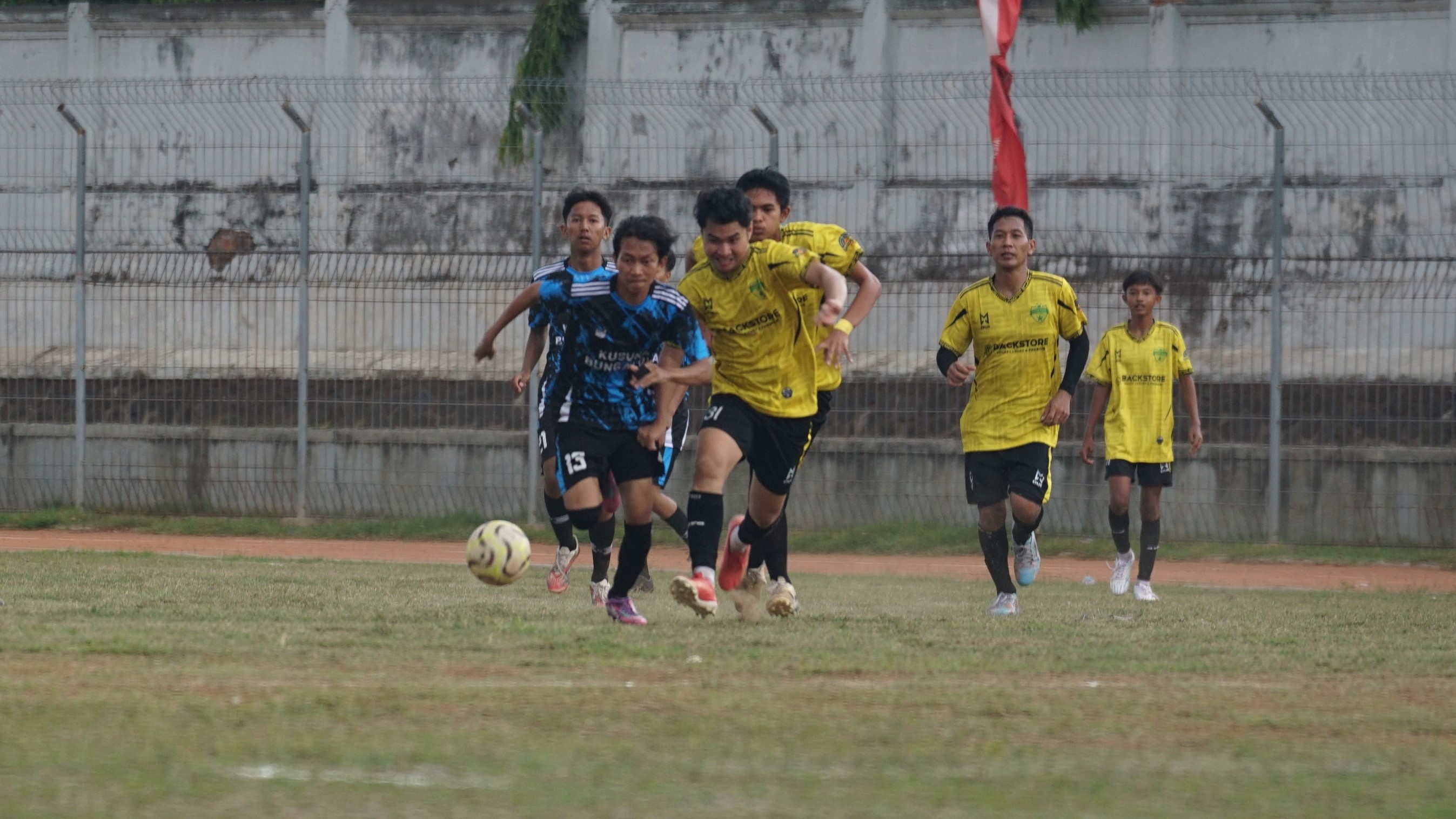 REBUT BOLA: Pemain Tunas Harapan Pengastulan (biru) dibayangi Putra Fajar Patas (kuning) dalam kompetisi Liga 2 PSSI Buleleng di Stadion Mayor Metra Singaraja, Rabu (12/11/2025).