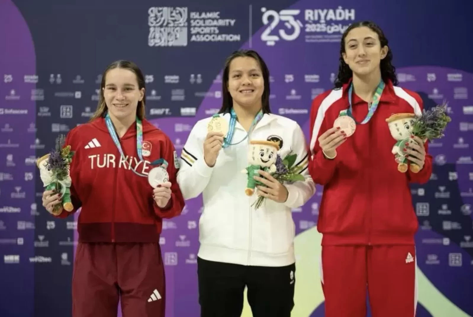 Perenang muda Indonesia, Adellia (tengah), menunjukkan medali emas yang diraihnya di nomor 200 meter gaya dada putri pada ajang ISG Riyadh 2025.