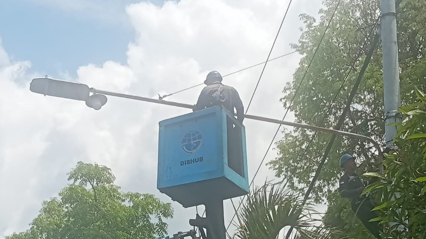 PEMELIHARAAN LAMPU: Petugas Dinas Perhubungan Buleleng melakukan pemasangan lampu penerangan jalan.