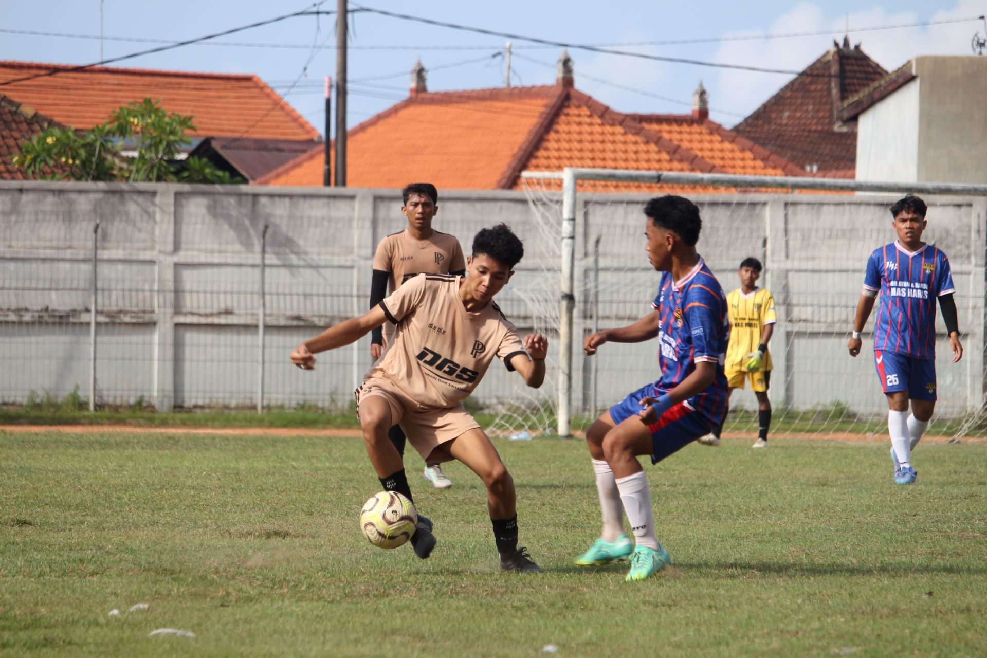 TANPA BALAS: Pemain Putra Penarukan (cokelat) berusaha menghindari pemain Tuan Muda FC Banyupoh (biru), dalam kompetisi Liga 3 PSSI Buleleng.