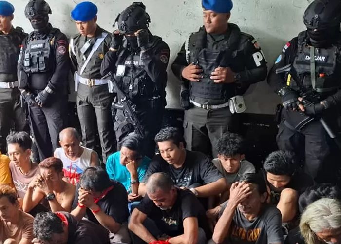 Petugas BNN berjaga di belakang para terduga pengedar narkoba yang berhasil diamankan saat operasi besar di kawasan Kampung Berlan.