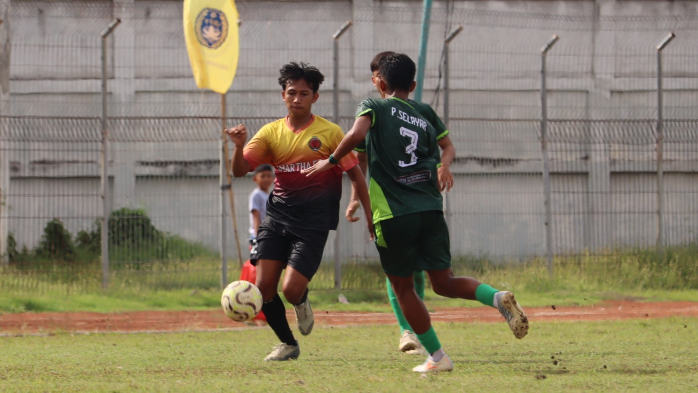 AMANKAN BOLA: Pemain Amartha FC Patas (kuning) menggiring bola berusaha lepas dari kawalan Putra Selayar Kampung Baru (hijau) dalam pertandingan di Stadion Mayor Metra, Minggu (30/11/2025).