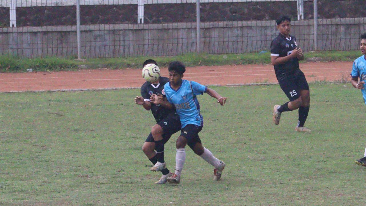 AMANKAN BOLA: Pemain Satria Tunas Jaya Sudaji (biru) berusaha mengamankan bola dari kejaran pemain Temukus FC (hitam) dalam pertandingan di Stadion Mayor Metra Singaraja, Selasa (2/12/2025).