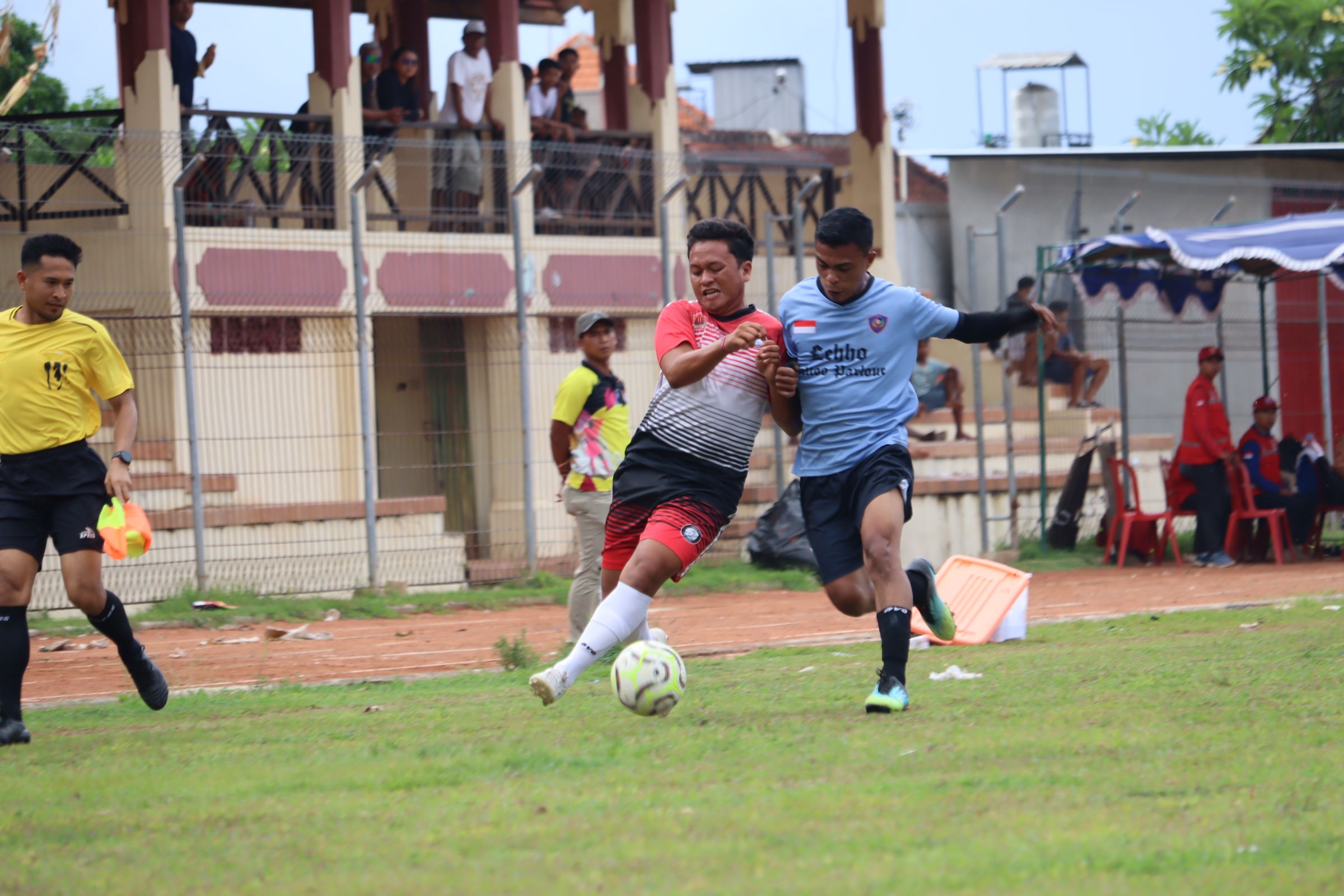 MAIN IMBANG: Pemain Forkal Kalibukbuk (merah putih) mengawal bola dari pemain Putra Kubutambahan (biru).