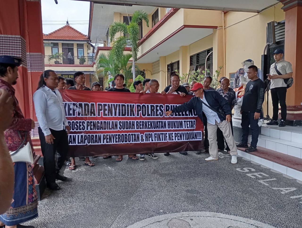BENTANGKAN SPANDUK: Warga membentangkan spanduk di Polres Buleleng pertanyakan kelanjutan laporan terkait kasus tanah Batuampar.