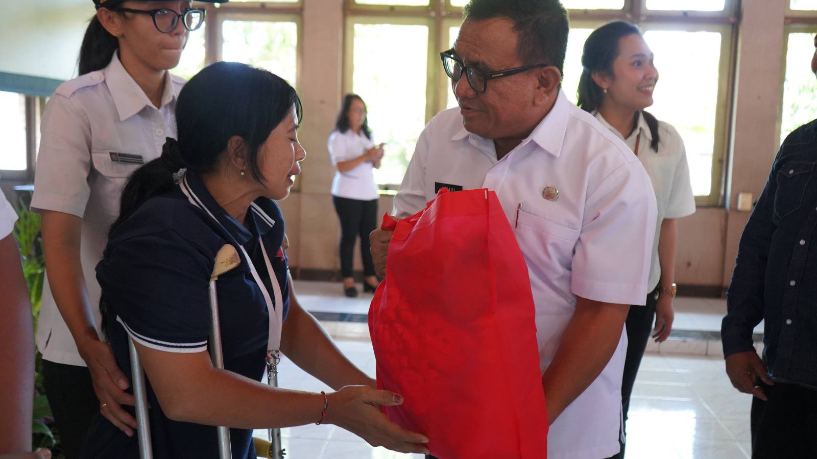 SERAHKAN BANTUAN: Asisten Pemerintahan dan Kesejahteraan Rakyat Setda Buleleng, Putu Ariadi Pribadi (kanan) menyerahkan bantuan pada seorang disabilitas di Buleleng.