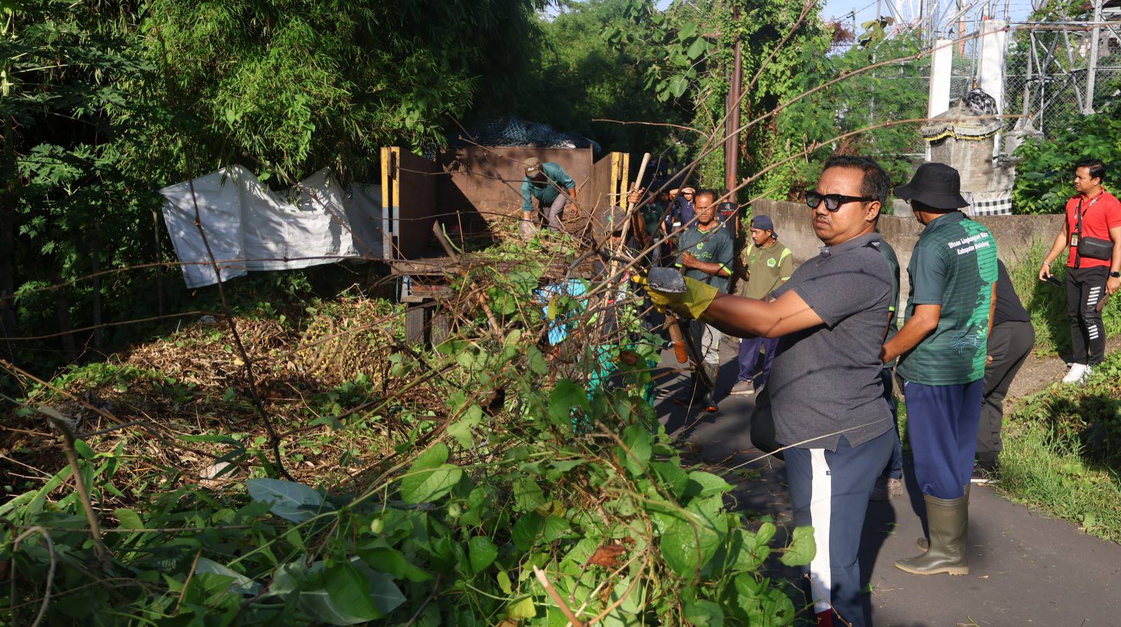 BERSIHKAN SAMPAH DAN BELUKAR: Warga bersama ASN, Polri, dan TNI membersihkan sampah dan semak belukar di kawasan Jalan Gunung Lempuyang, Kelurahan Banjar Tegal.