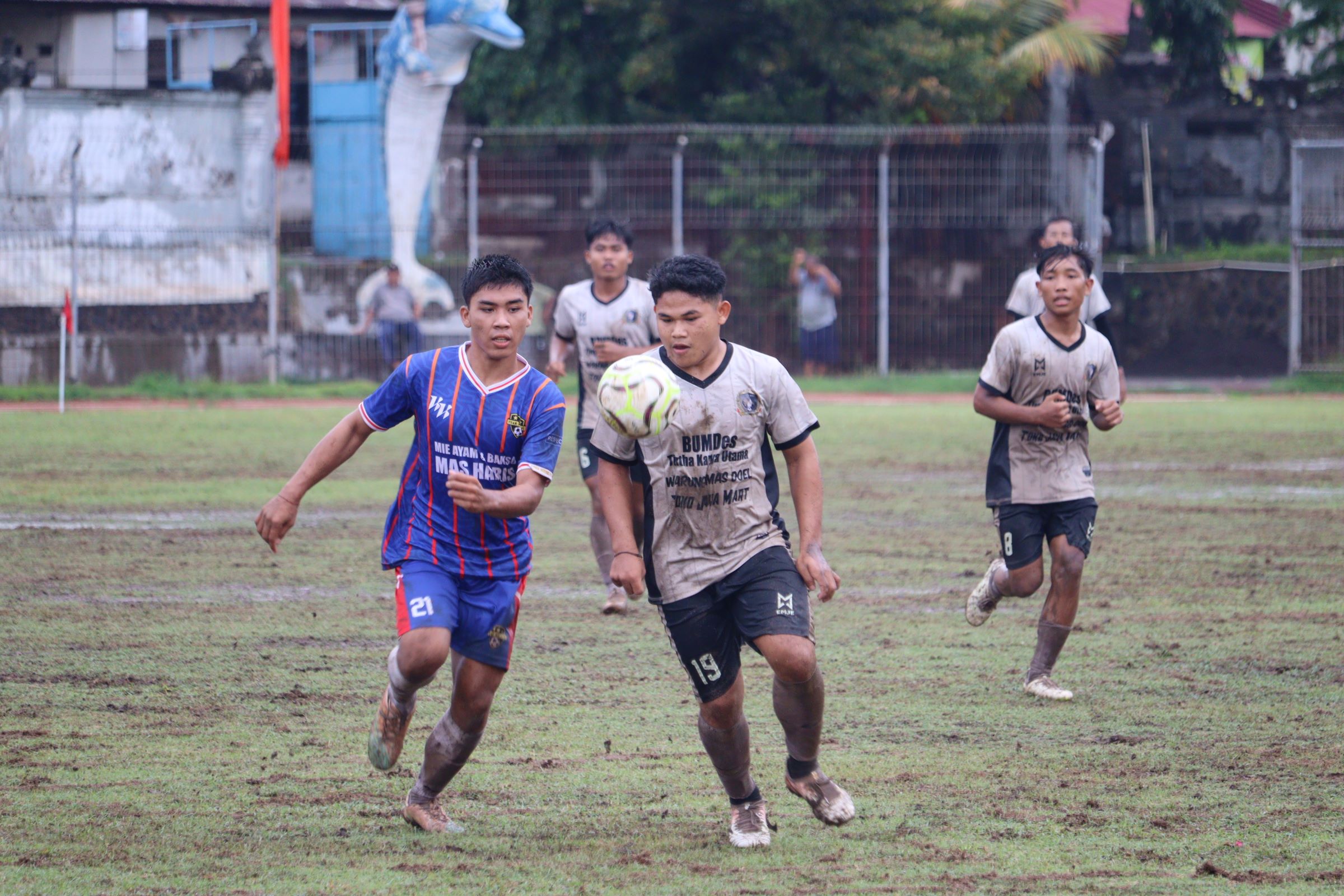KE BABAK KNOCK OUT: Pemain Suka Bali FC Sumberklampok, Darsa Darma (putih) mengawal bola dari kejaran pemain Tuan Muda Banyupoh, Putu Agus Wirastawan (biru) dalam pertandingan di Stadion Mayor Metra.