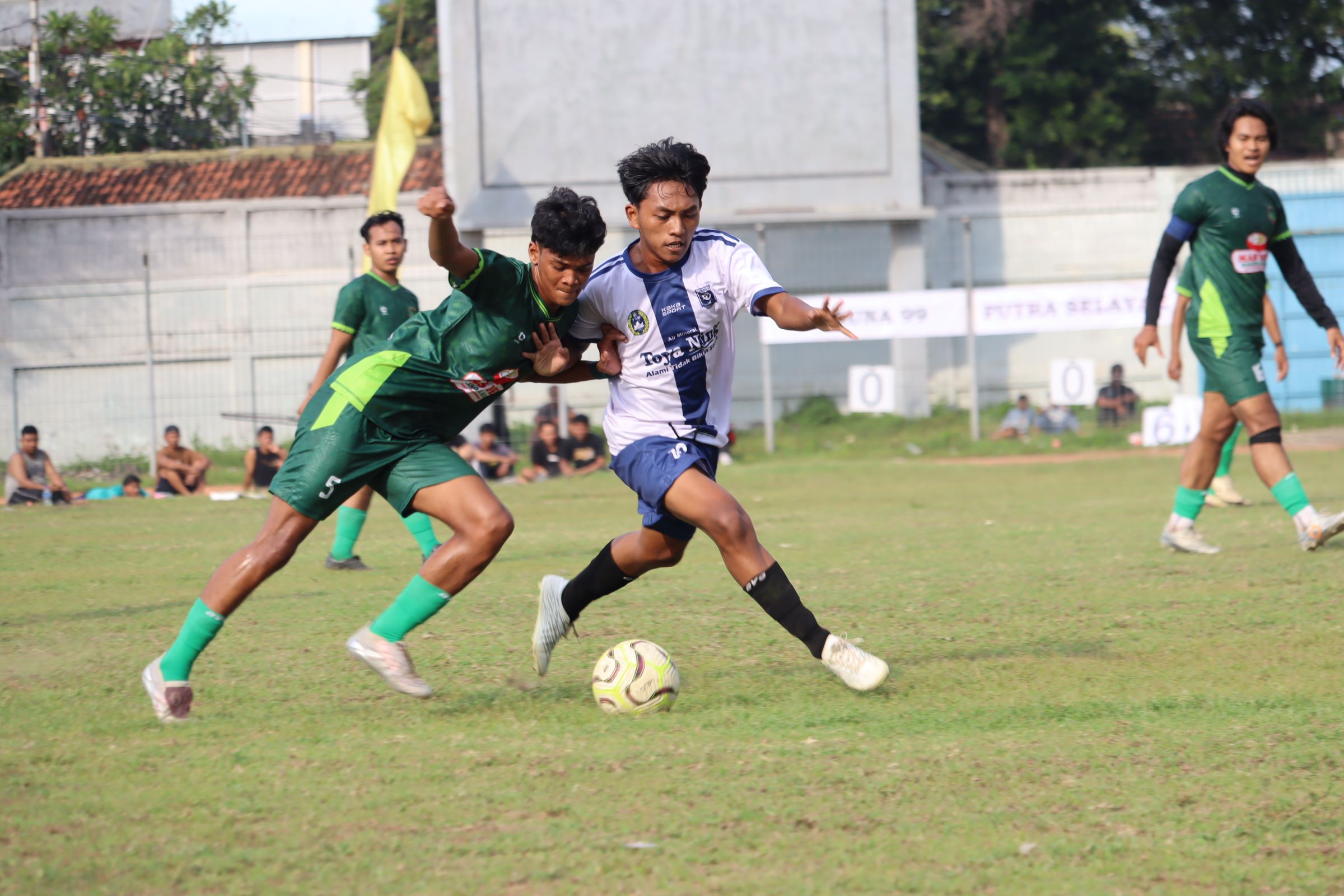 AMANKAN BOLA: Pemain Putra Selayar Kampung Baru (hijau) berusaha mengamankan bola dari pemain Taruna 99 Celukan Bawang (putih) dalam pertandingan Liga 1 PSSI Buleleng, pada Minggu (7/12/2025).